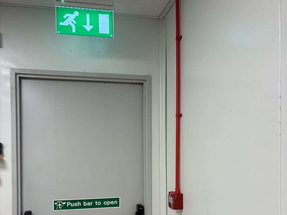 Fire exit door with emergency exit sign and red fire cable